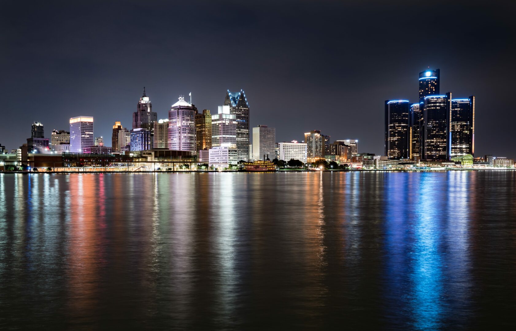 A city skyline at night with lights reflecting on the water.