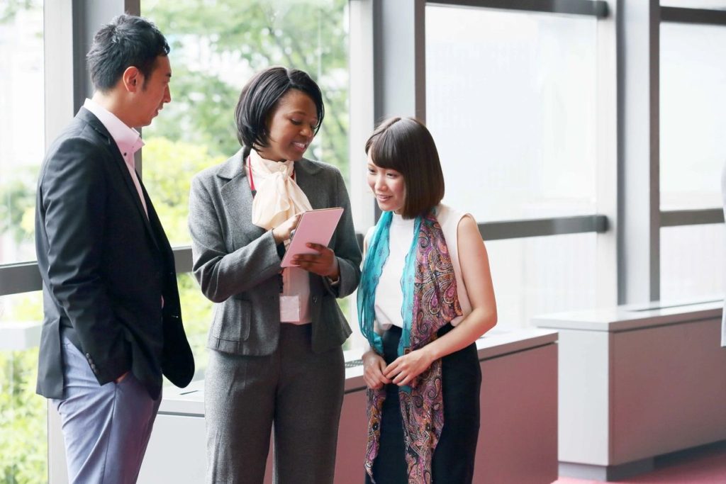 Three people standing in a room talking to each other.